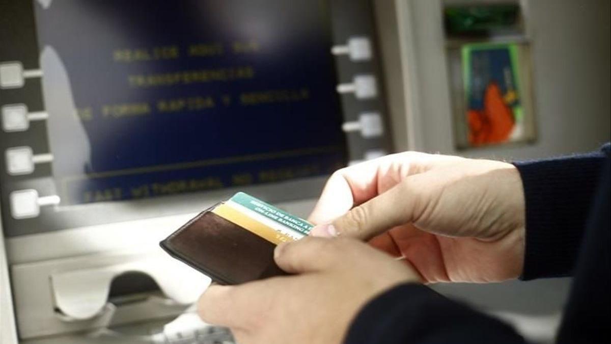 Un hombre sacando dinero en un cajero.