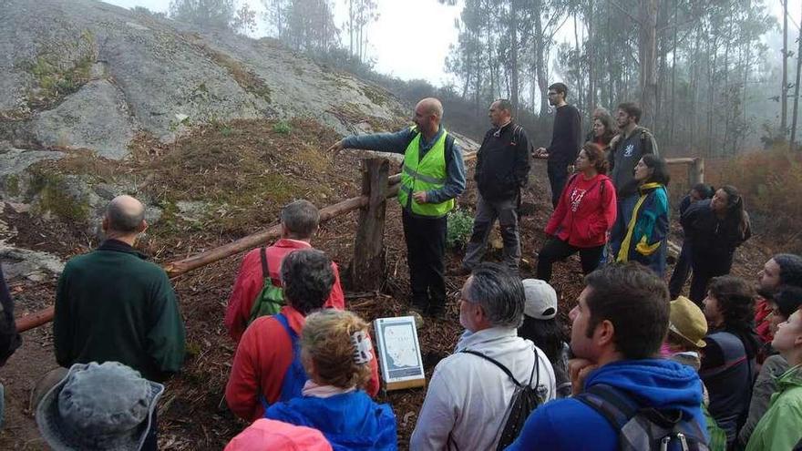 El arqueólogo Xurxo Constenla da explicaciones a un grupo de visitantes a los petroglifos de Trasmañó.