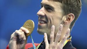 Phelps muestra su medalla señalando los cuatro oros que ha conseguido hasta ahora