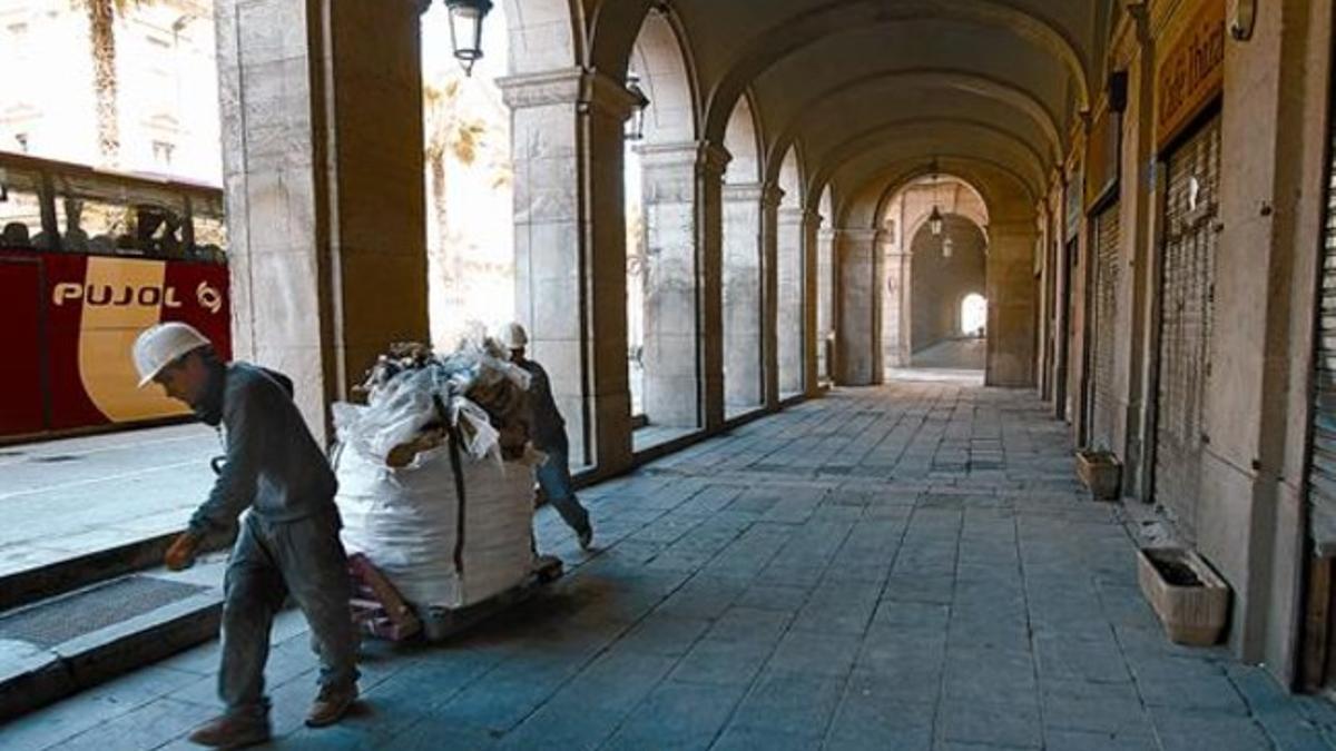 Obras 8 Dos trabajadores retiran una bolsa llena de escombros de una de las fincas en rehabilitación del entorno de los porches de Xifré.