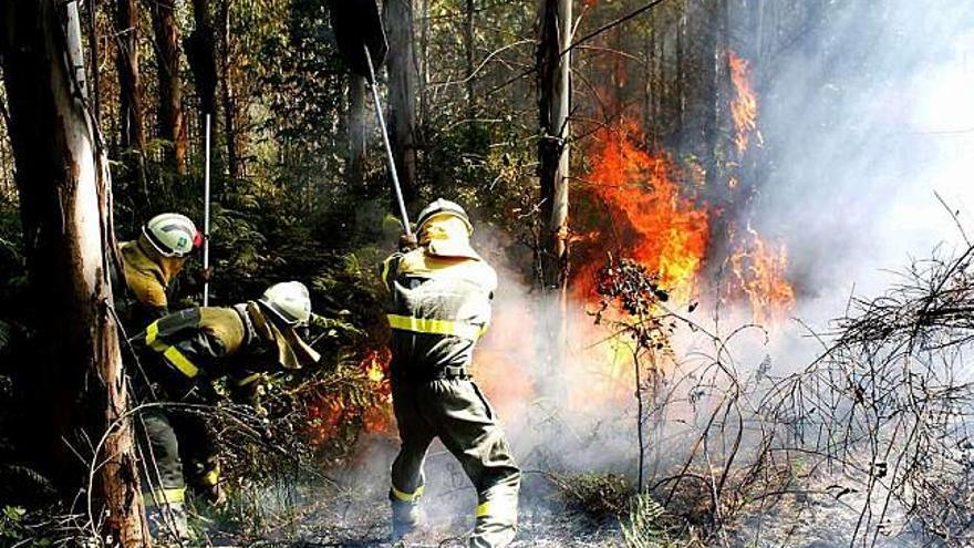 Varios operarios intentan el miércoles sofocar las llamas en un incendio en Vilasantar. / efe