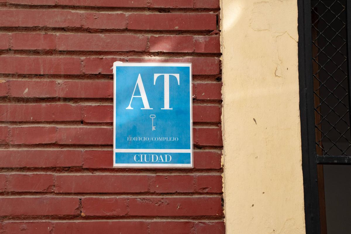 Cartel con las siglas ‘AT’ en la fachada de un edificio, correspondiente a ‘Apartamento Turístico’