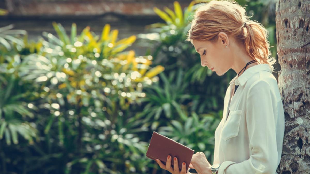 Chica leyendo en un jardín