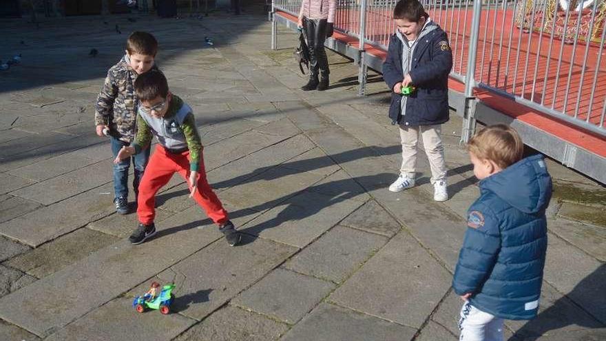 Varios niños juegan con un coche teledirigido en la Praza da Ferrería. // Rafa Vázquez