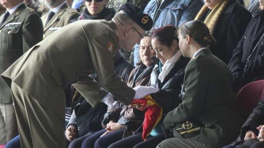 La viuda recibe la bandera plegada al final de la ceremonia.