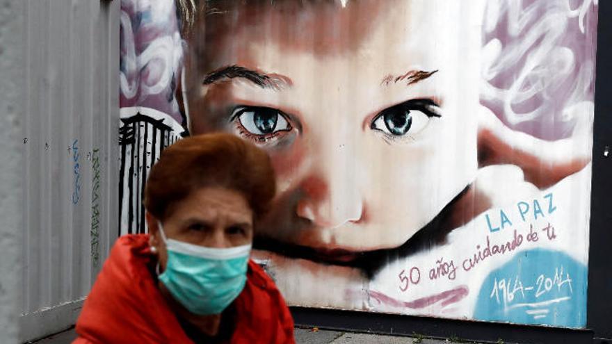 Una mujer, con mascarilla, pasa por delante de un mural en el Hospital La Paz de Madrid.