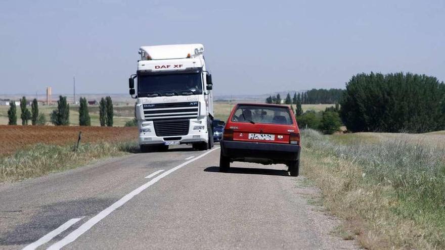 Un camión y un coche se cruzan a duras penas en la carretera de La Bóveda a Cañizal.