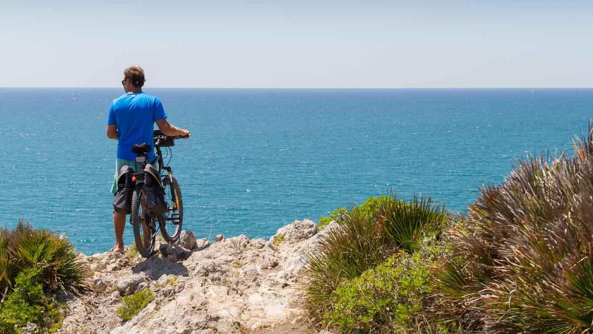 Un ciclista se toma un descanso frente al mar en el camino GR-92, entre Sitges y Vilanova.