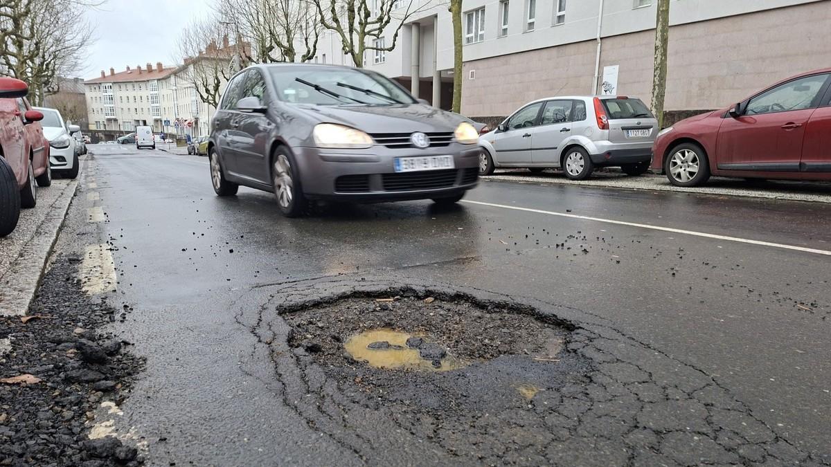 Un vehículo evita la profunfa fochanca de la rúa Lisboa, en Fontiñas
