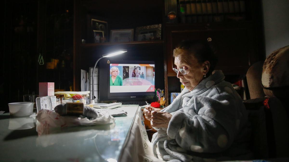 Cristi Morte teje en su hogar, con la televisión de fondo y su querido perro. Ella vive sola, aunque recibe visitas de su familia.