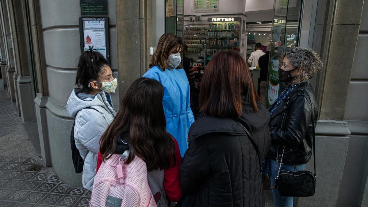 La farmacéutica Lourdes Egea atiende a pie de calle a dos madres y a sus hijas.