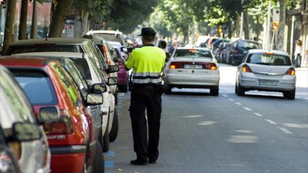Un empleado de BSM impone una sanción a un vehículo aparcado en la zona azul de la calle de Girona.