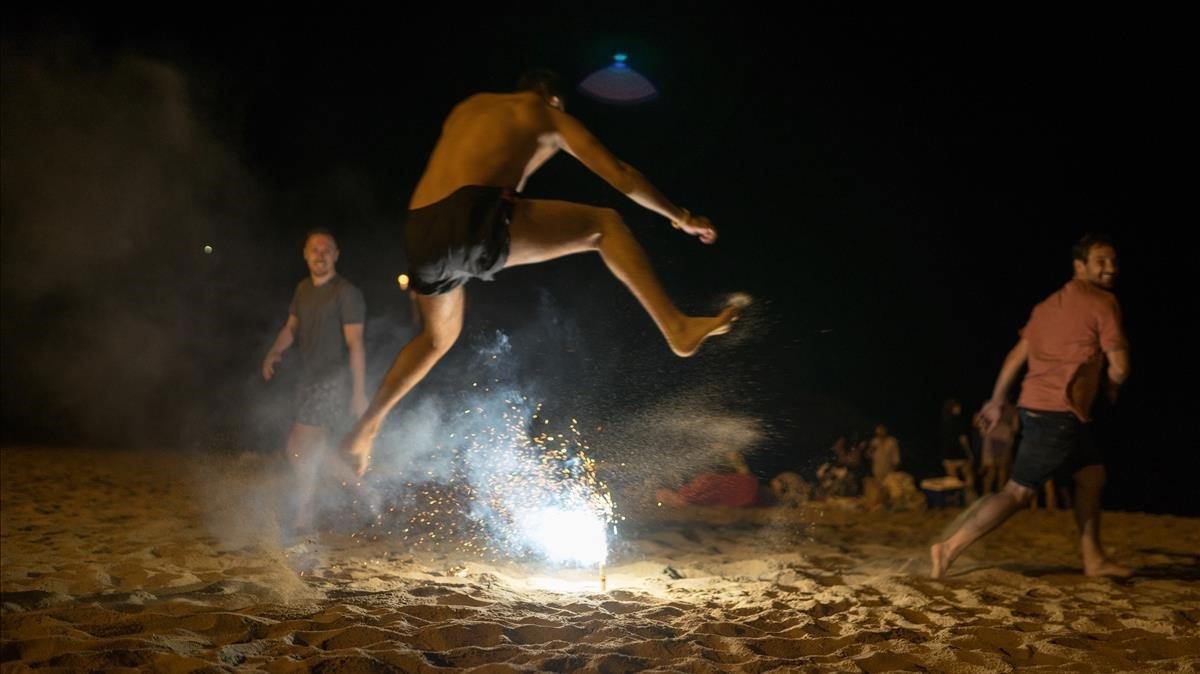 Jóvenes saltando la hoguera en la playa de Palamós.