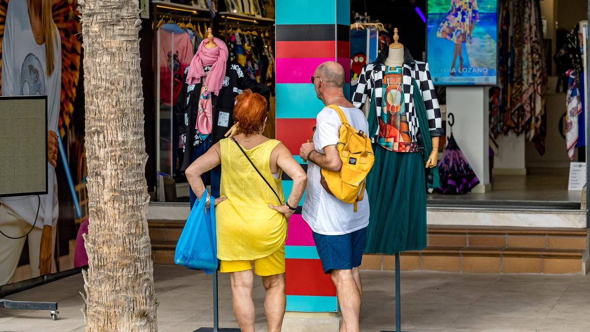 Dos personas miran ropa en un comercio de Benidorm.