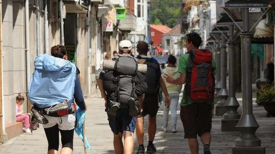 Unos peregrinos pasean por la Calle Real de Caldas. // G.S.