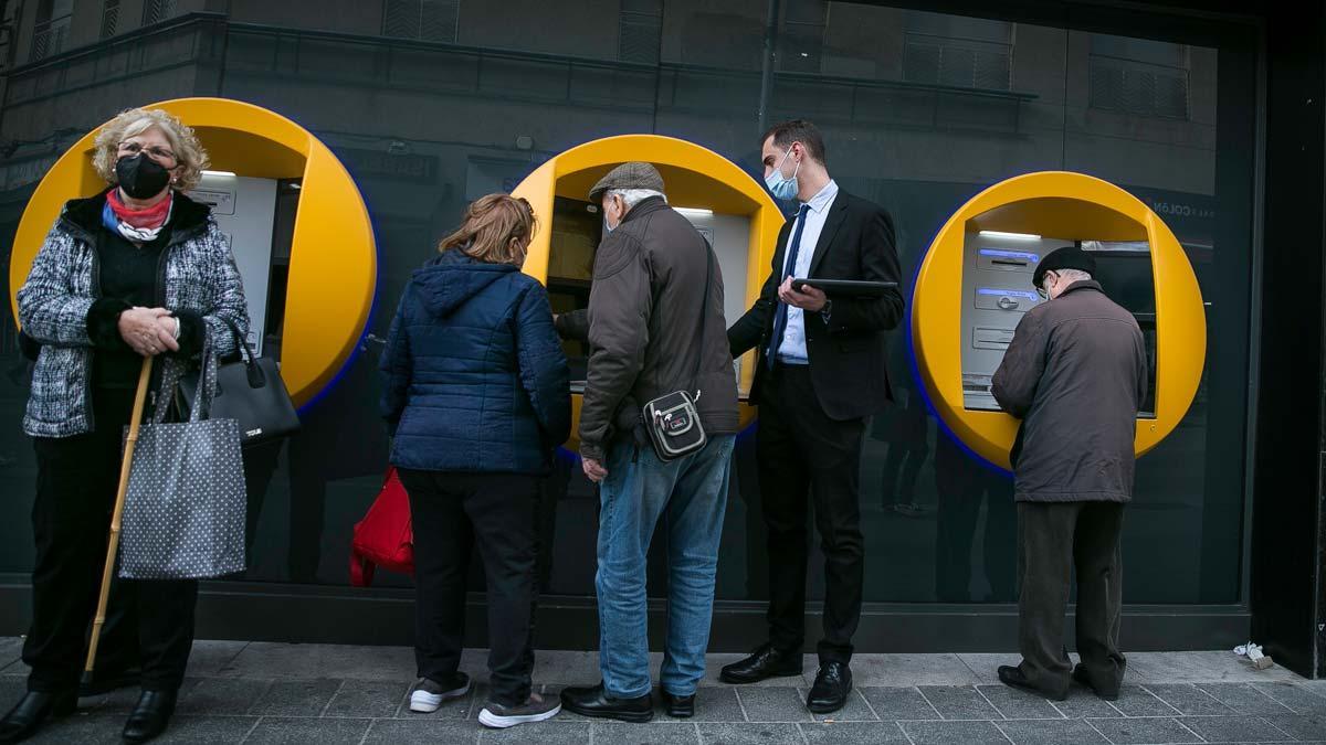 Usuarios realizando operaciones en unos cajeros automáticos en Barcelona