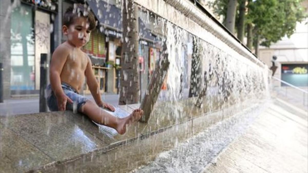 Al fresco 8 Un niño juega con el agua, ayer en una plaza de Barcelona.