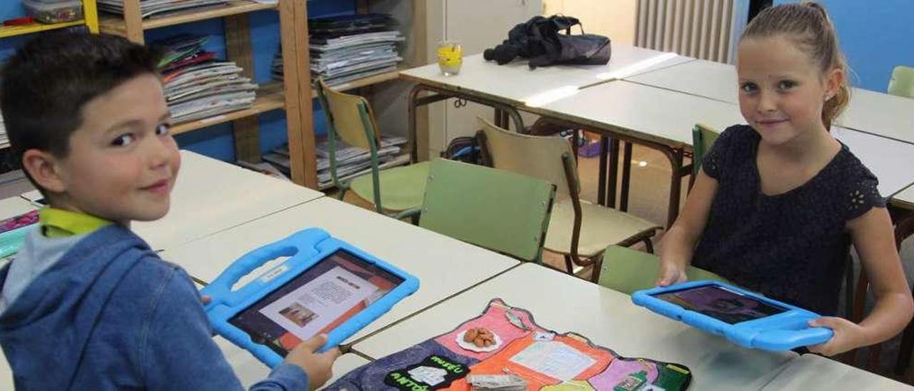 Arriba, Aitana Echevarría y Álvaro Correas, con sus tablets; a la izquierda, Begoña García muestra un trabajo de los alumnos.