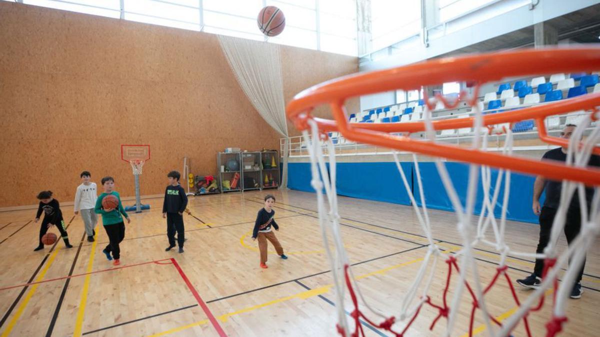 Varios niños juegan a baloncesto en el polideportivo de Can Guerxo.