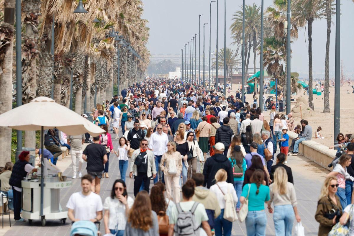 Decenas de turistas yt vecinos pasean por el paseo marítimo de València este domingo.