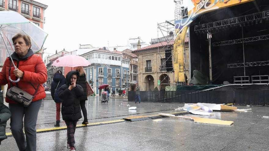 Varios paseantes, ante el escenario de la plaza del Parche, con elementos desprendidos.