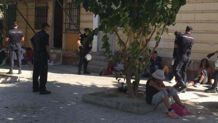 Los sospechosos, sentados en el suelo, junto con agentes, en la puerta del &#039;chalé&#039;.