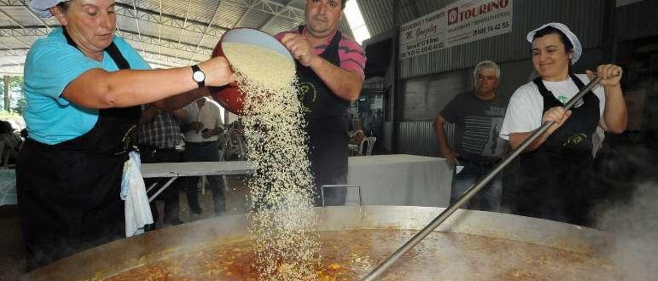 Los cocineros terminan de echar arroz a la gran paella. // Iñaki Abella