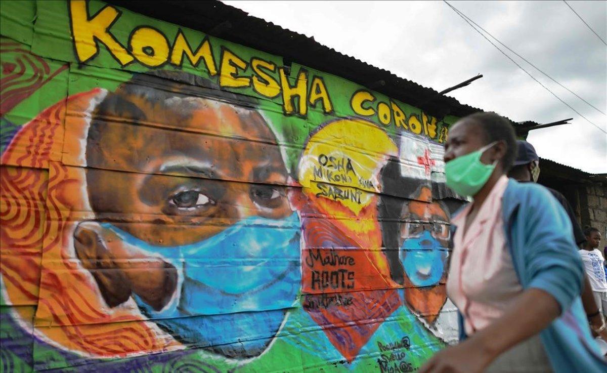 Una mujer con mascarilla pasa delante de un mural en el que se apela a tomar medidas de seguridad ante la expansión del coronavirus, en Nairobi, Kenia.