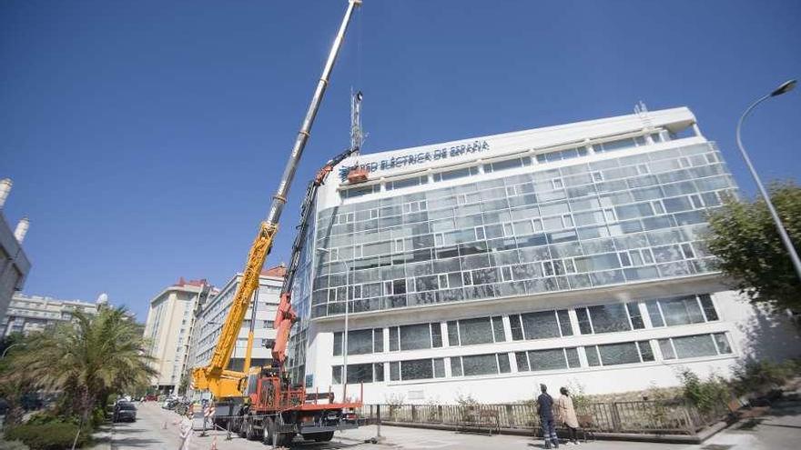 Una grúa inicia la retirada de las letras Red Eléctrica de España en la fachada de su sede en la ciudad.