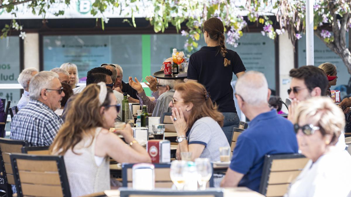 Una camarera atiende a los clientes de una terraza en Alicante.