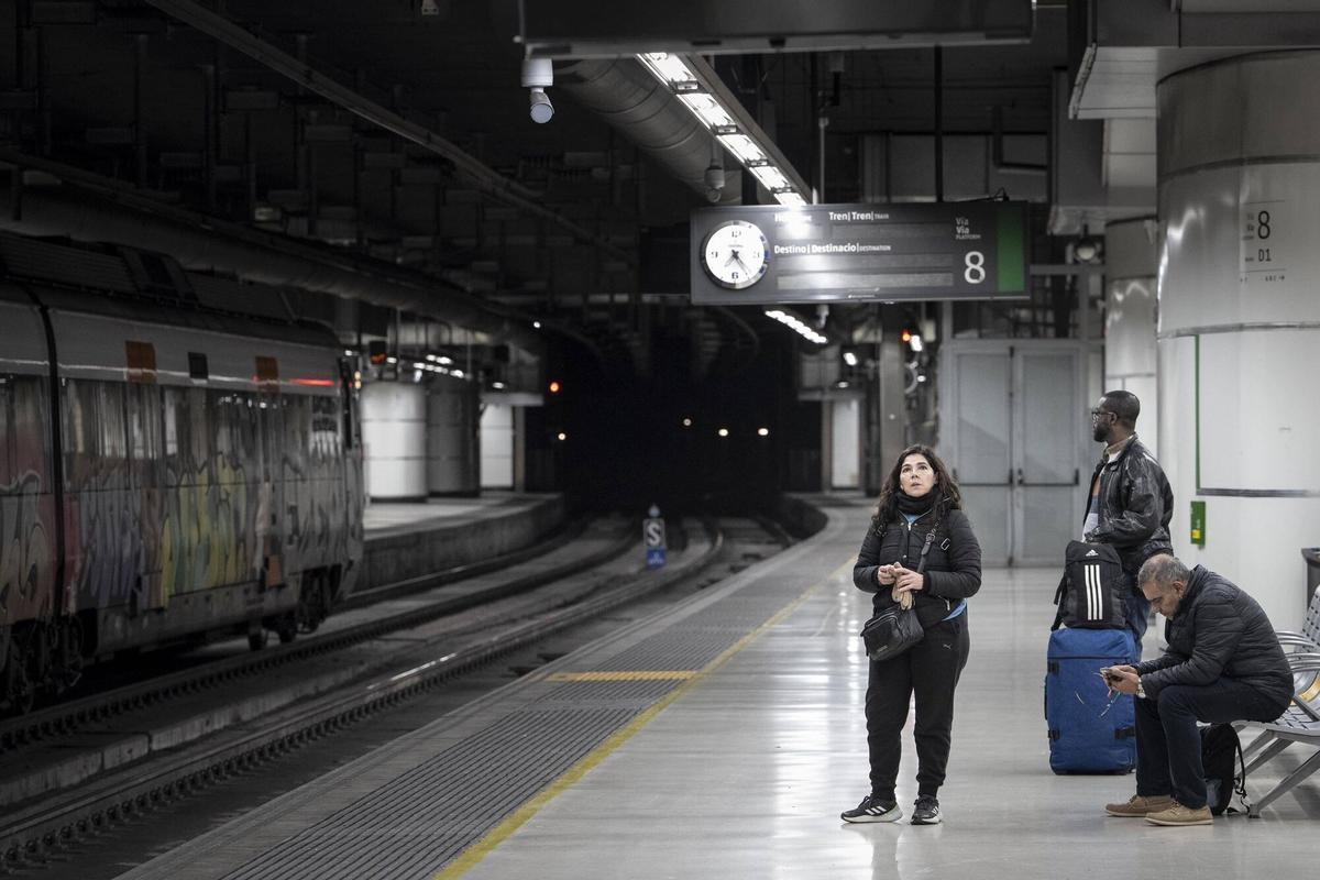 Barcelona 26/01/2026 Nueva jornada de caos en Rodalies por la cancelación de trenes a primera hora de la mañana por una avería en el centro de control. En la foto, unos pasajeros junto a un tren parado en un anden de la estación de Sants a las 7.23 , que ha anunciado su salida pero se ha cancelado Fotografía de Ferran Nadeu