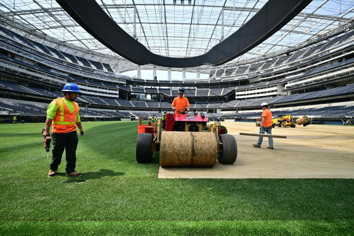 Los trabajadores instalan césped en el campo en el SoFi Stadium en Inglewood, California, antes de su cambio de nombre temporal al Estadio de Los Ángeles para la Copa del Mundo el 13 de mayo de 2026.