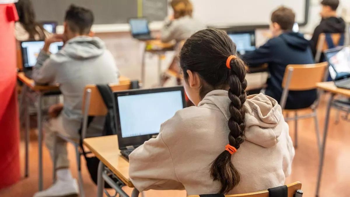 Un grupo de alumas y alumnos trabajan en clase con sus ordenadores, en un instituto.