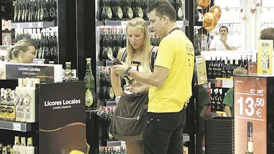 Clientes de una tienda del área ´duty free´ del aeropuerto de Palma, delante de expositores con botellas de alcohol.