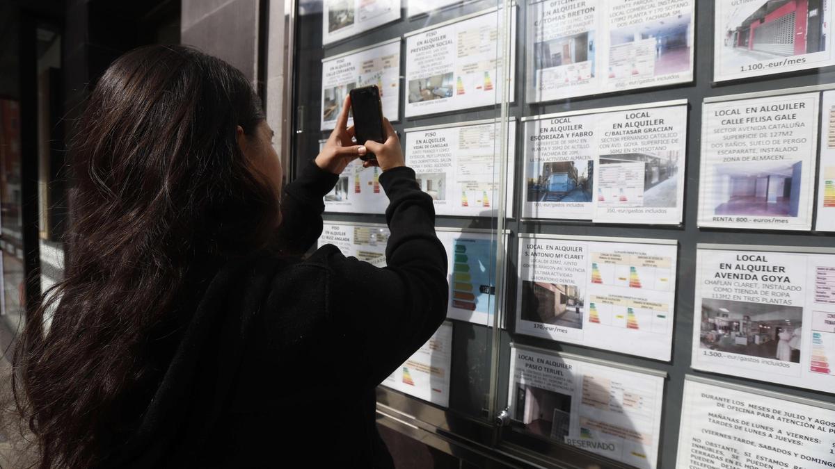 Una mujer fotografía ofertas de alquiler en Zaragoza.