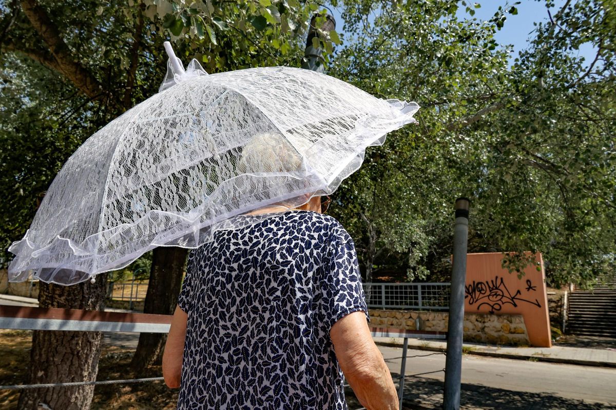 Una mujer se protege del sol con una pequeña sombrilla.
