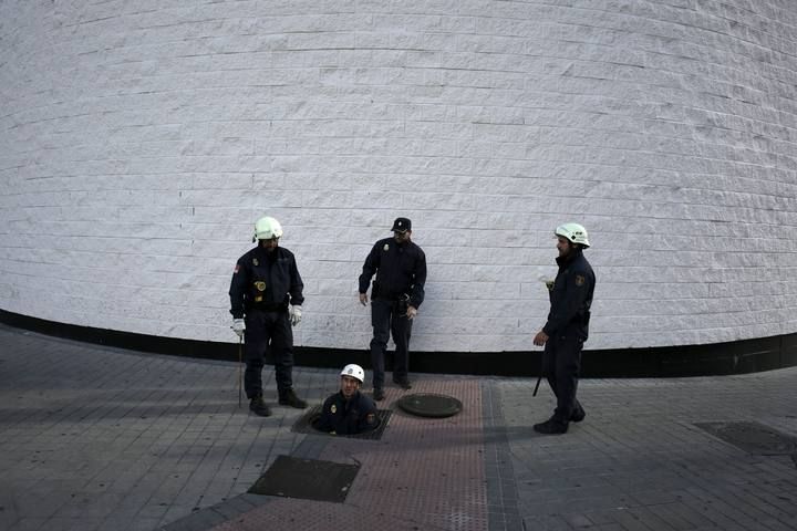 Policemen check a drain outside the Santiago Bernabeu stadium before the 'Clasico' soccer match between Real Madrid and Barcelona in Madrid, Spain