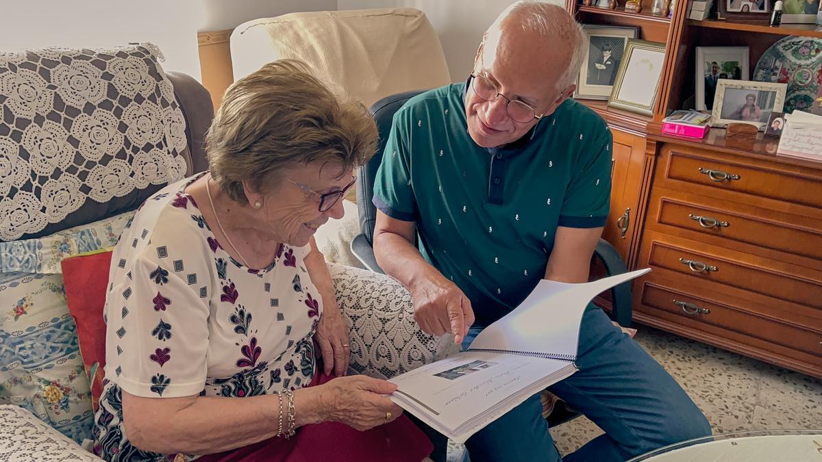 Guillermo Bolívar, voluntario, mira un libro junto a Rosa Sánchez mientras charlan, en la casa de esta.