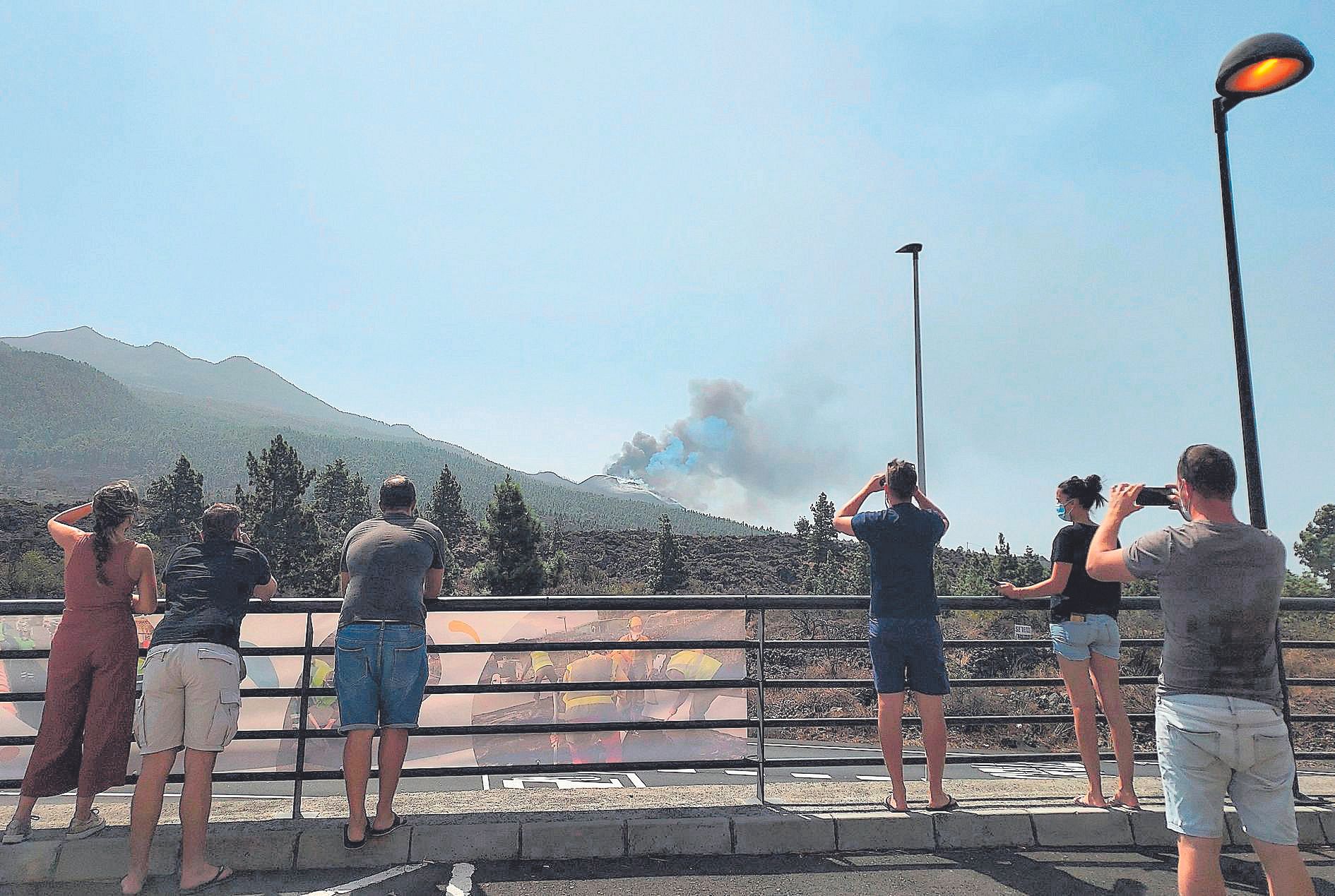 Un grupo de curiosos sacan fotos de la erupción del volcán.