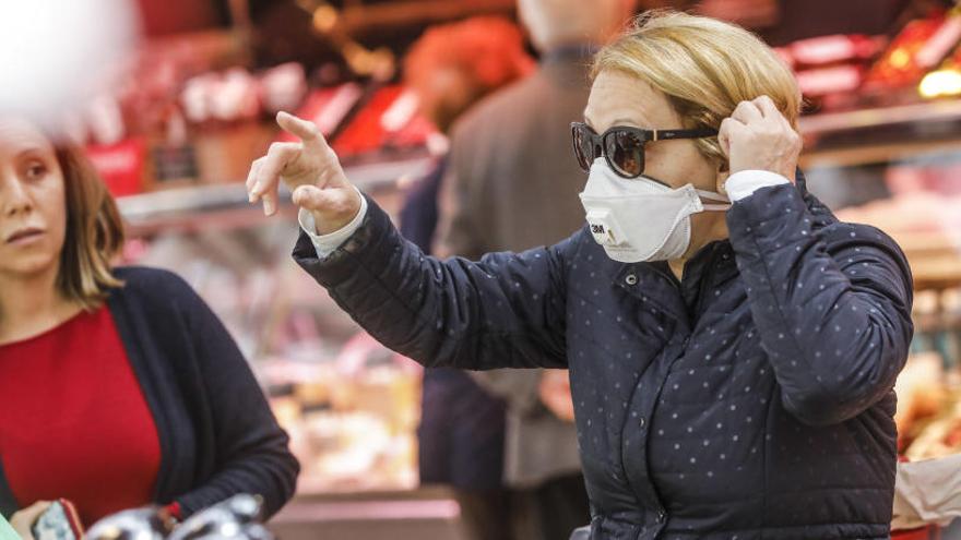 Una mujer comprando en un supermercado con una mascarilla