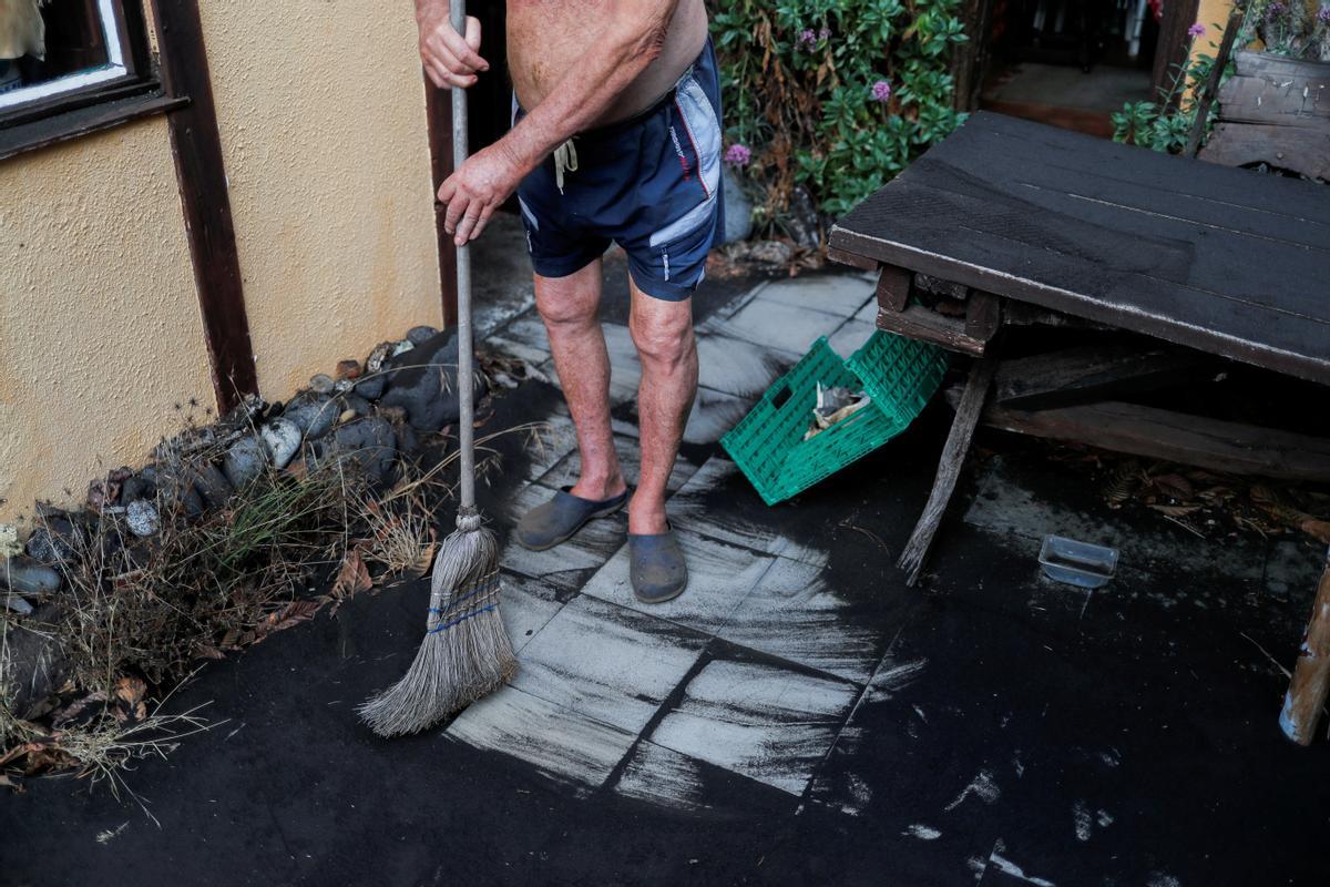 El residente alemán limpia la ceniza a la entrada de su casa en Tacande de Arriba, La Palma.