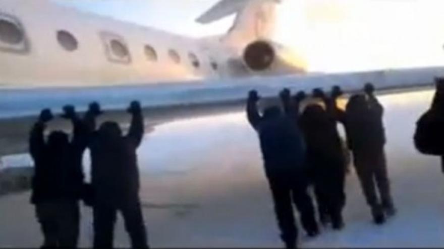 Unos pasajeros empujan su avión para que despegue
