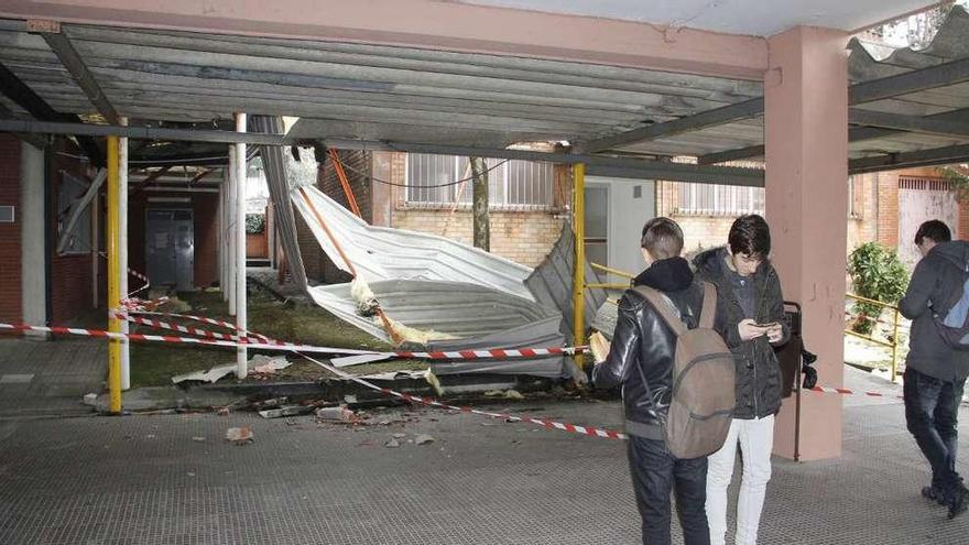 Varios alumnos del centro escolar contemplan la cubierta derribada por el viento. // S.A.