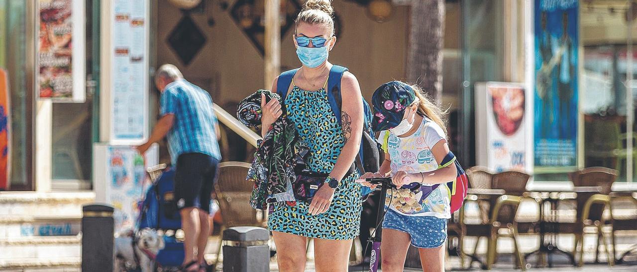 Una madre camina con su hija por el paseo de la playa de Benidorm