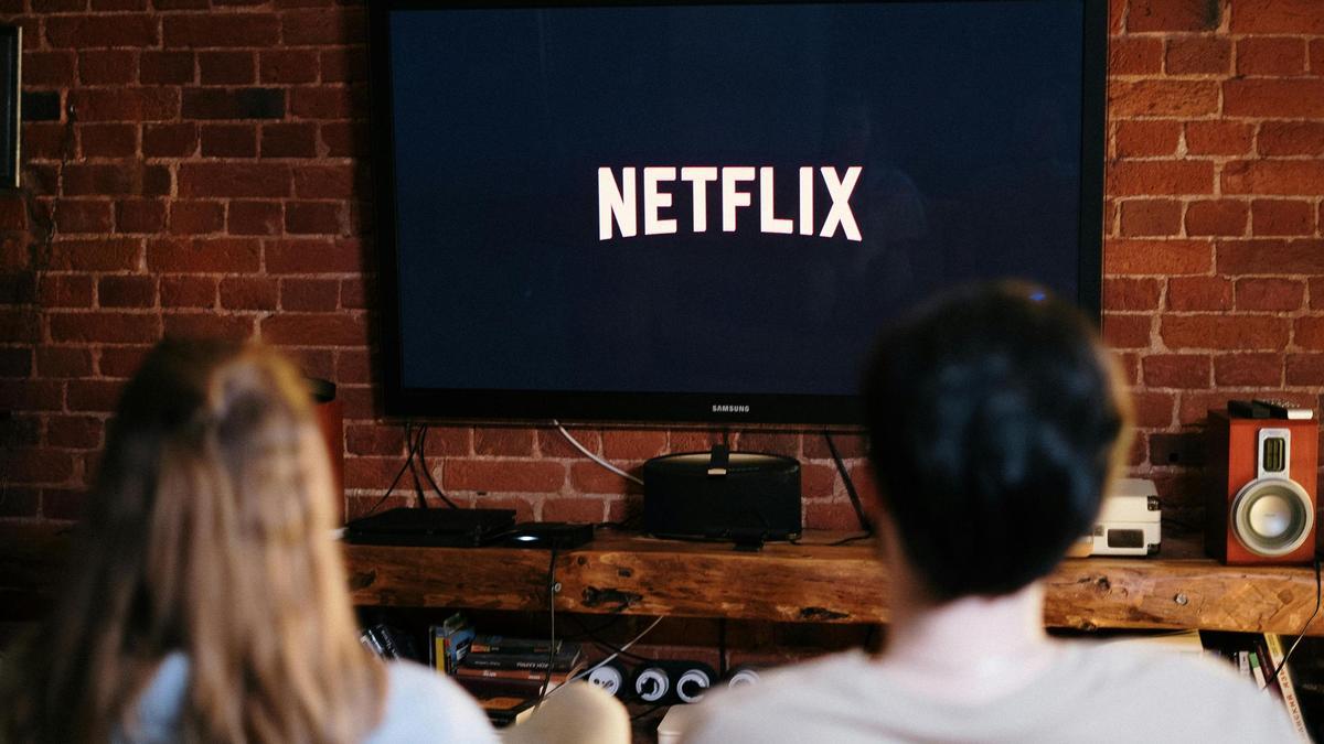 Una pareja de jóvenes ve Netflix en el salón.