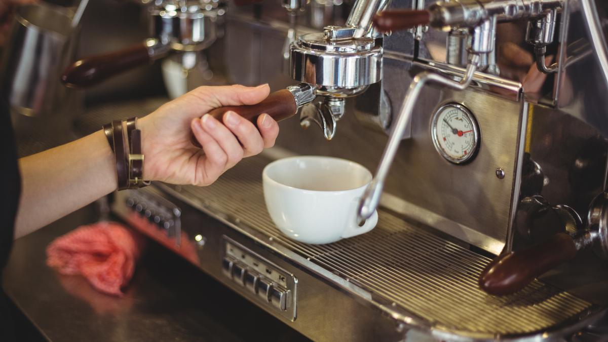 Una camarera preparando un café.