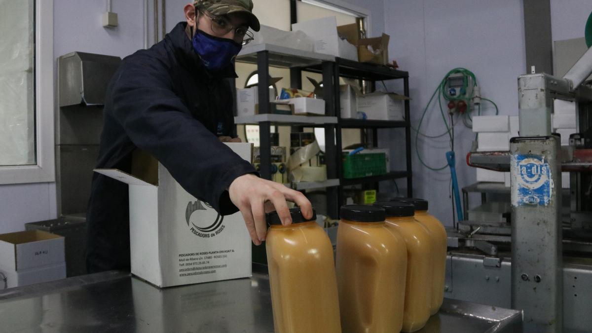 Un treballador guardant pots de fumet amb envas de plàstic a la planta de Roses