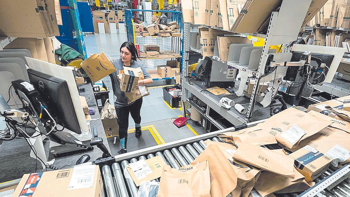 Una treballadora amb diversos paquets al centre logístic Amazon al Far
