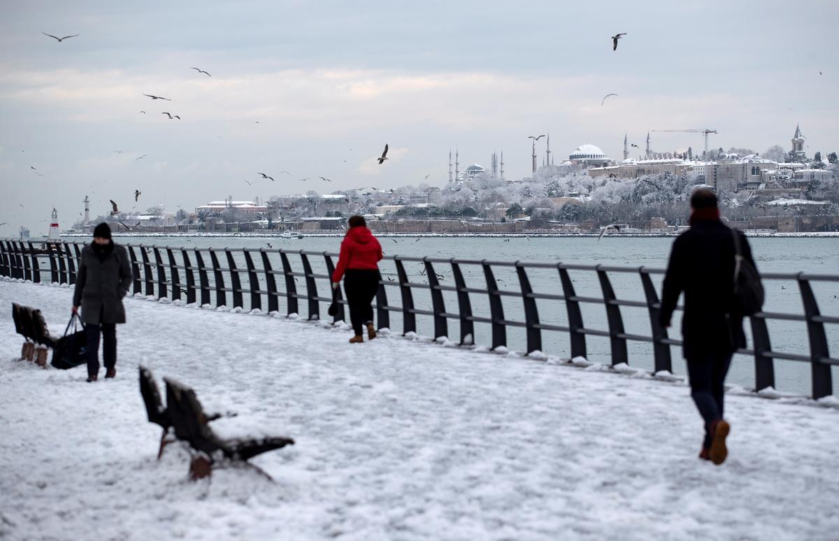 Ciudadanos pasean a la orilla del Bósforo, en un día nevado en Estambul.