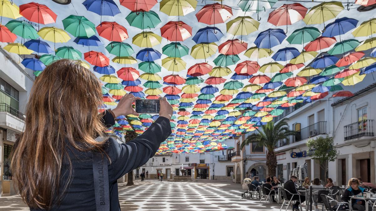 Una turista fotografía la Plaza de los Paraguas de Malpartida de Cáceres.